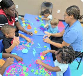 kindergarten teacher sitting with students in art class