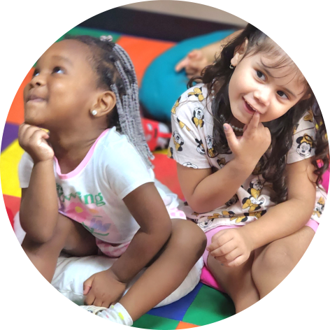 Two young girls are sitting on colorful mats