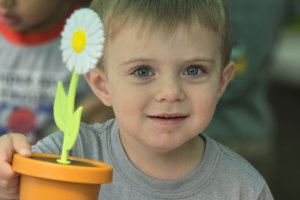 a young boy holding a toy flower pot